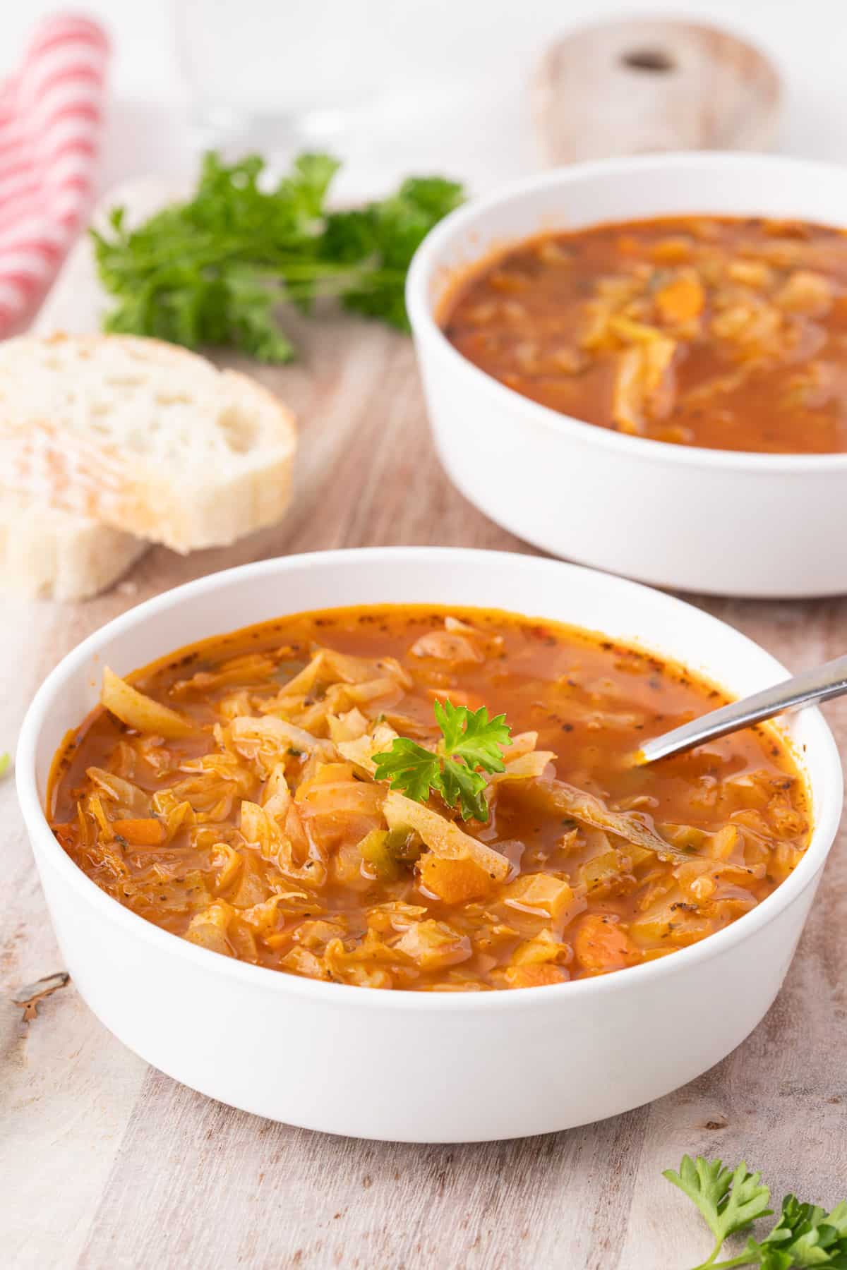 Two bowls of soup laid out on a wood board with bread.