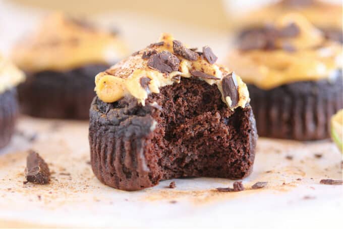 Chocolate muffin with a bite taken out and peanut butter spread on top.