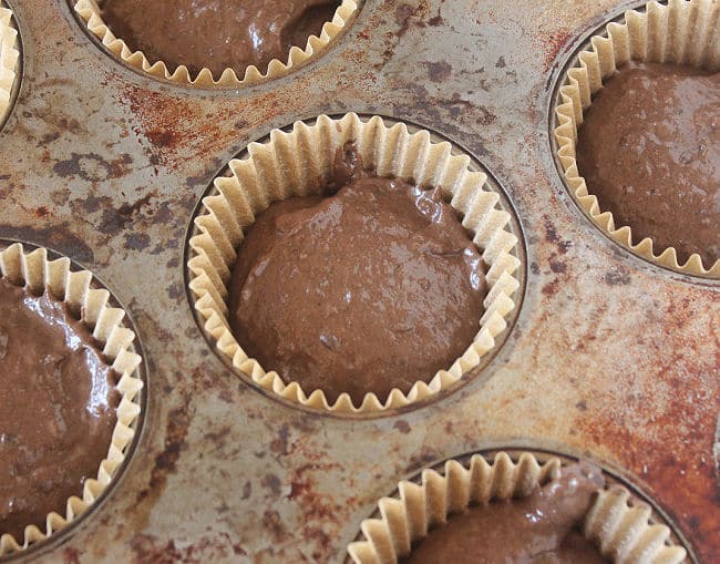 Unbaked chocolate cupcake batter in a muffin pan.