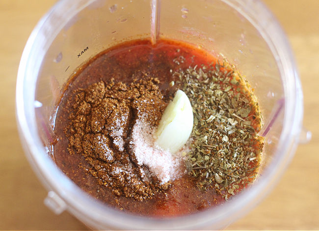 Tomato sauce, herbs, and garlic in a blender.