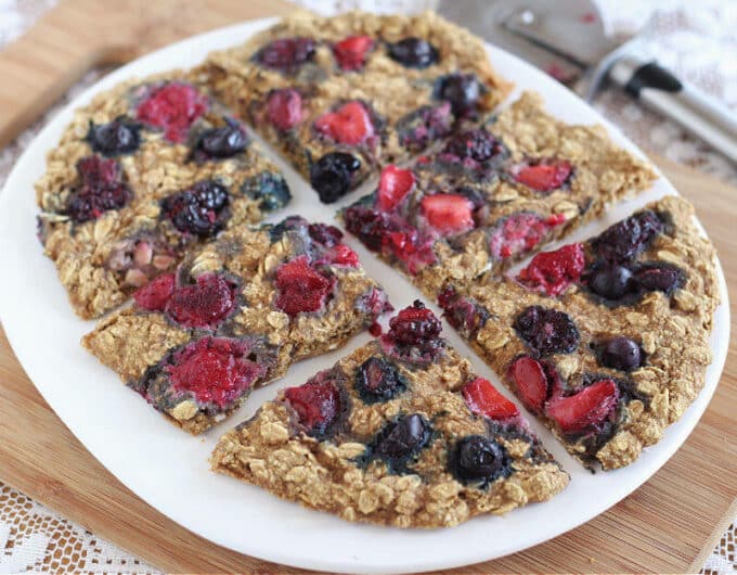 Berries on top of a flat bread served on a white plate.