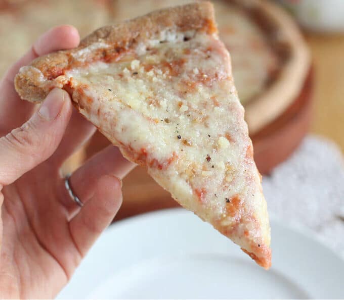 Hand holding a slice of pizza.