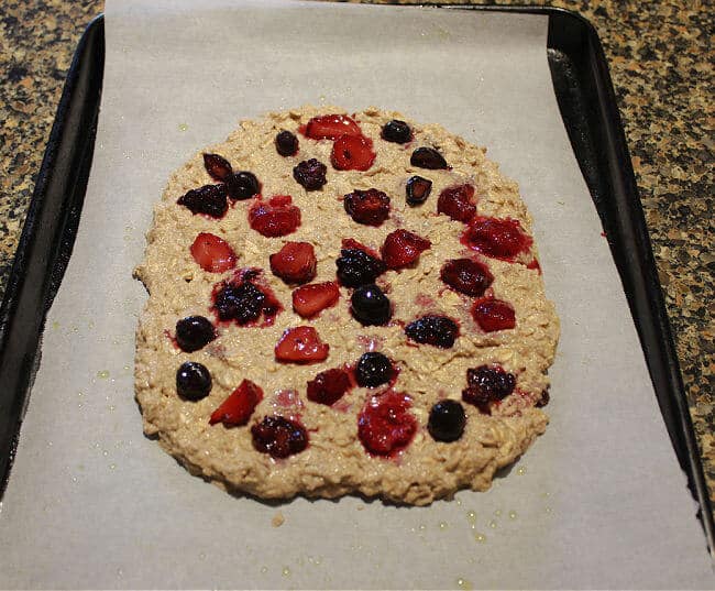 Oat flatbread with berries on top on a baking sheet.