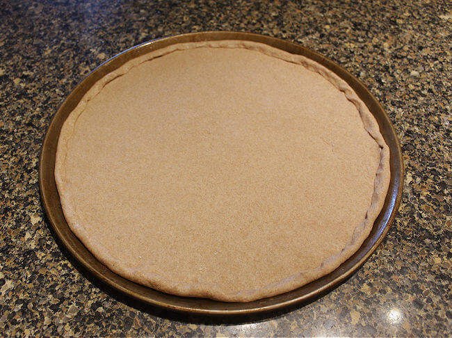 Pizza pan with unbaked pizza dough.