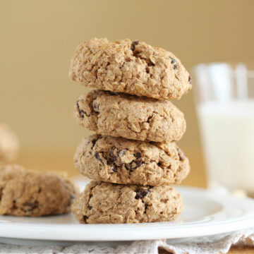 Stack of four chubby cookies on a white plate.