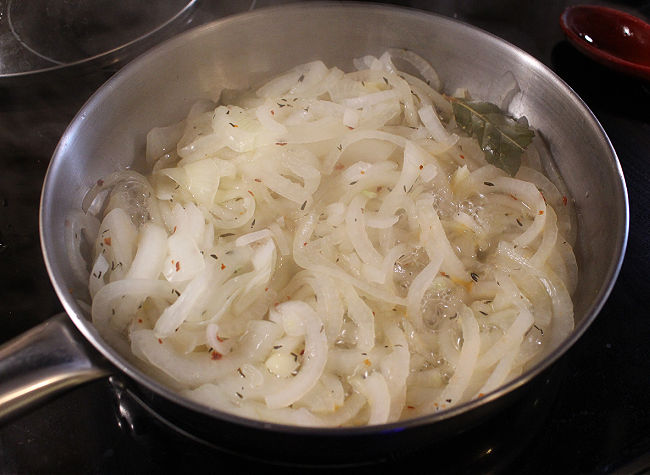 Onions sauteing in a steel pan.