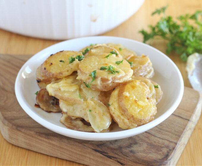 Sliced potatoes in a creamy sauce on a white plate.