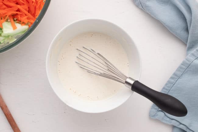 Whisking a dressing in a white bowl.