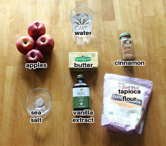 Various ingredients laid out on a wood table, including apples, cinnamon, and tapioca starch.