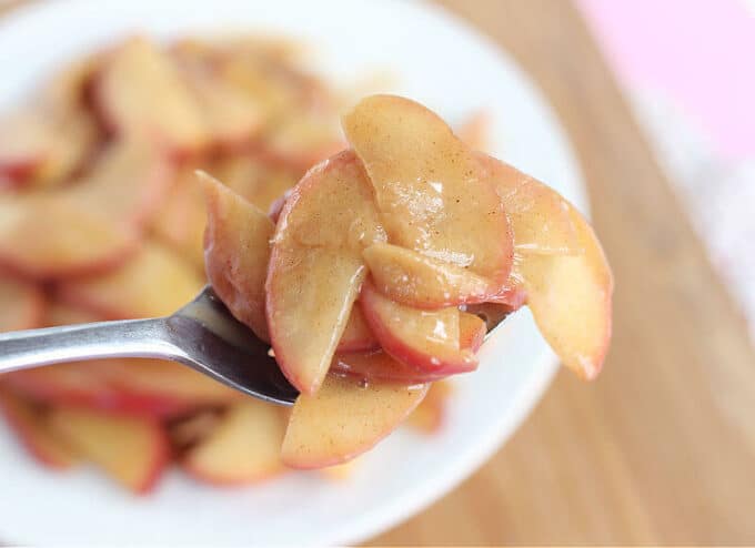 Saucy apple slices on a large silver spoon.
