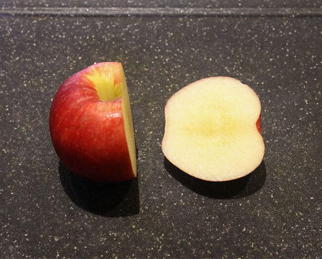 Cut apple on black cutting board.