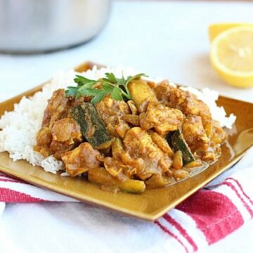 Indian chicken curry and white rice on a brown plate.