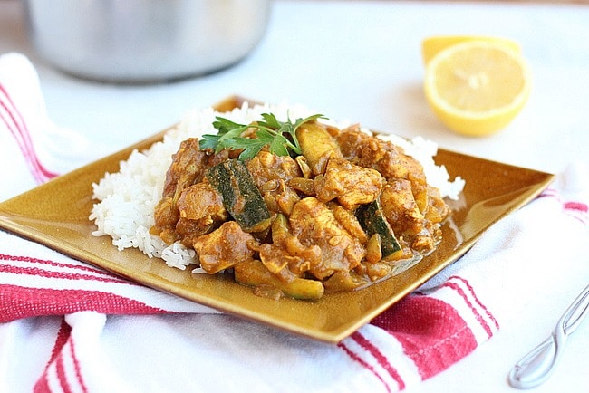 Indian chicken curry and white rice on a brown plate.