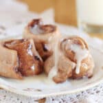 Three rolls with icing on a small white plate.