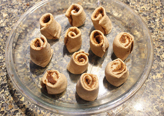 Unbaked cinnamon rolls in a glass pie plate.