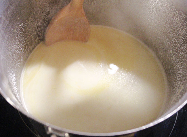 Wood spoon stirring a roux in a saucepan.