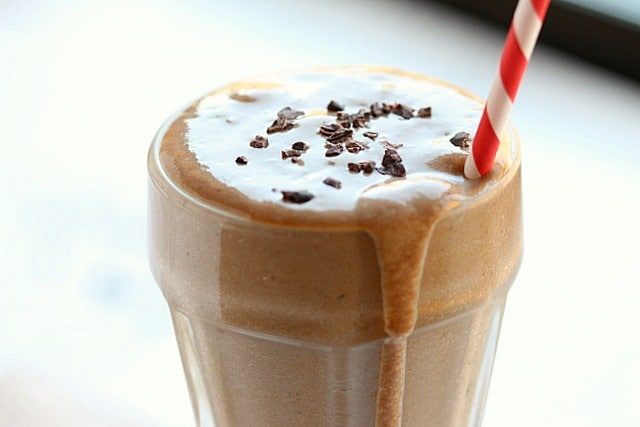 Chocolate milkshake overflowing out of a glass.