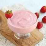 Strawberry chia frosty in a glass surrounded by strawberries.