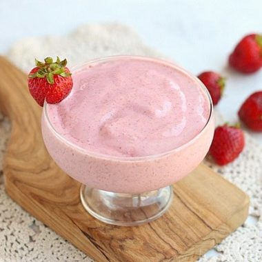 Strawberry chia frosty in a glass surrounded by strawberries.