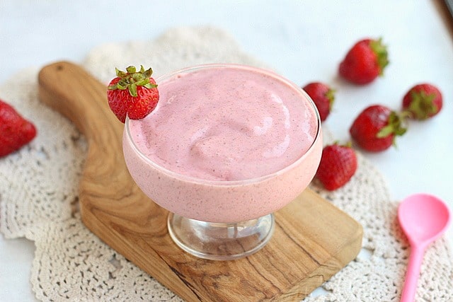 Strawberry chia frosty in a glass surrounded by strawberries.