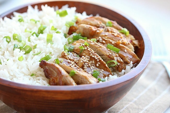 Teriyaki chicken bowl with rice and scallions.