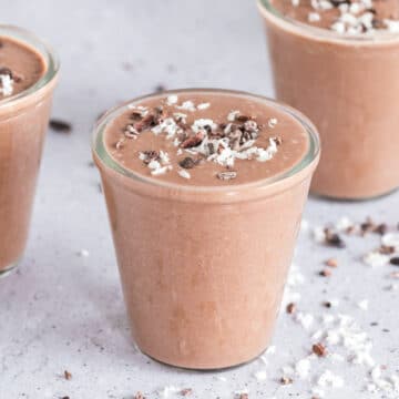 Three chocolate smoothies on a table.