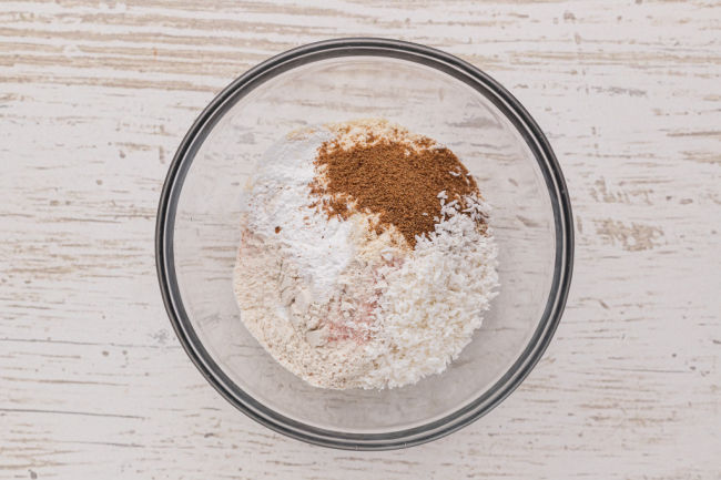 Flour, sugar, coconut, and baking powder in a bowl.