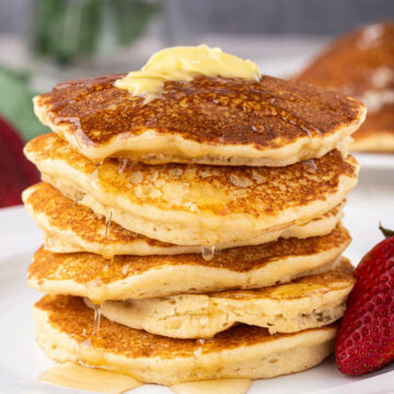 Stack of pancakes topped with butter and syrup.