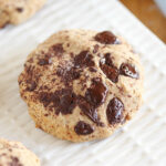 Chocolate chip cookie on a textured white plate.