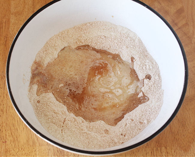 Flour with oil and maple syrup in a white bowl.