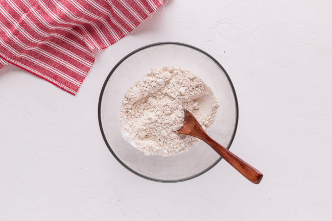 Flour, salt, and baking powder being stirred in a bowl.