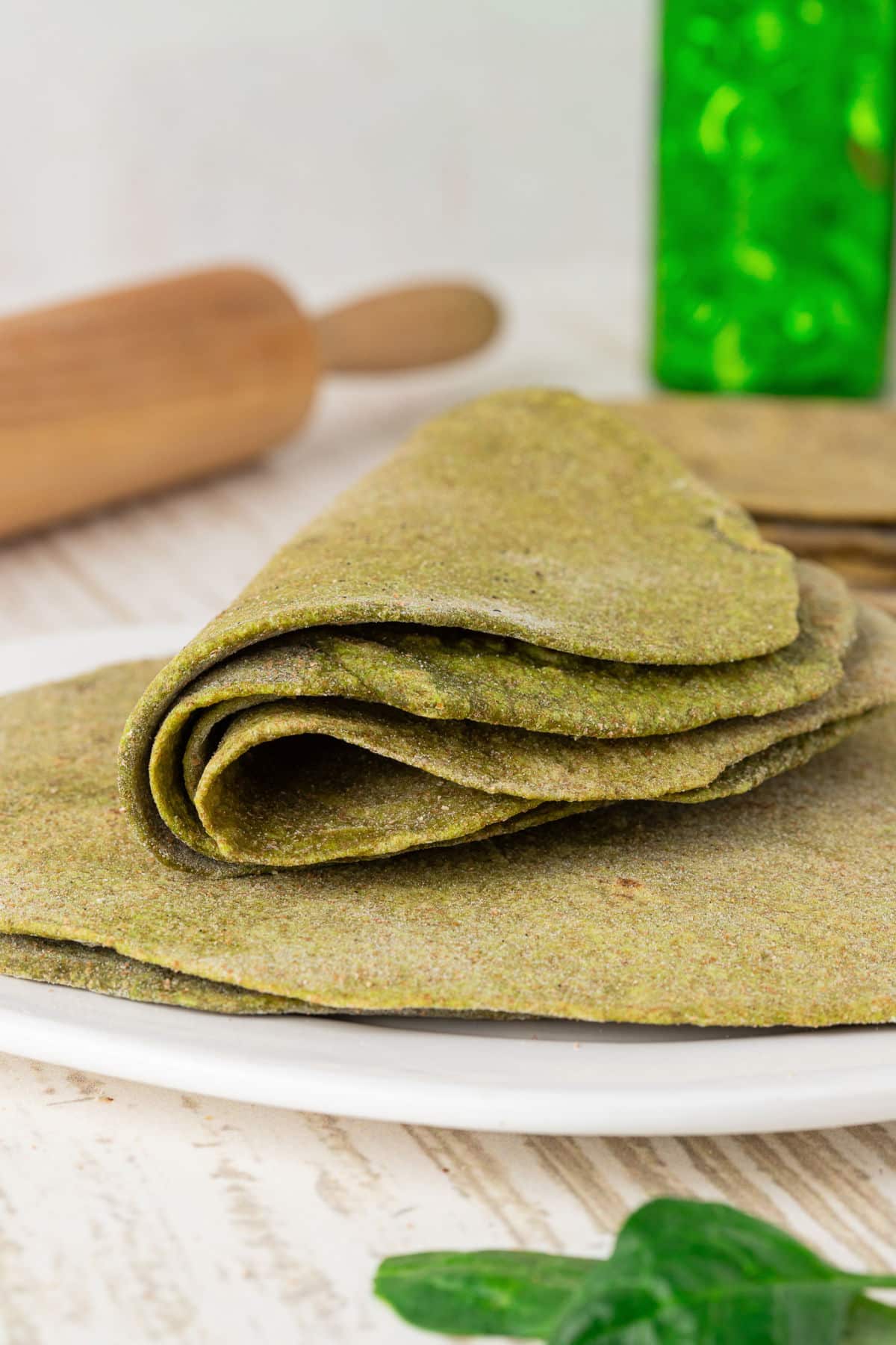 Folded bunch of spinach tortillas on a plate.