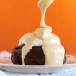 Peanut butter being drizzled over a small chocolate cake.