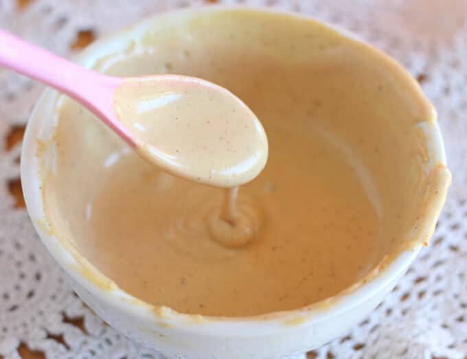 Peanut butter on a pink spoon in a white bowl.