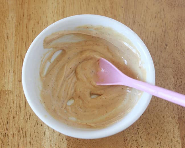 Stirring peanut butter in a bowl with a pink spoon.