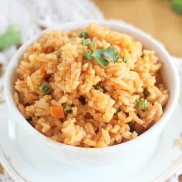 Bowl of Mexican rice with peas in a white bowl.