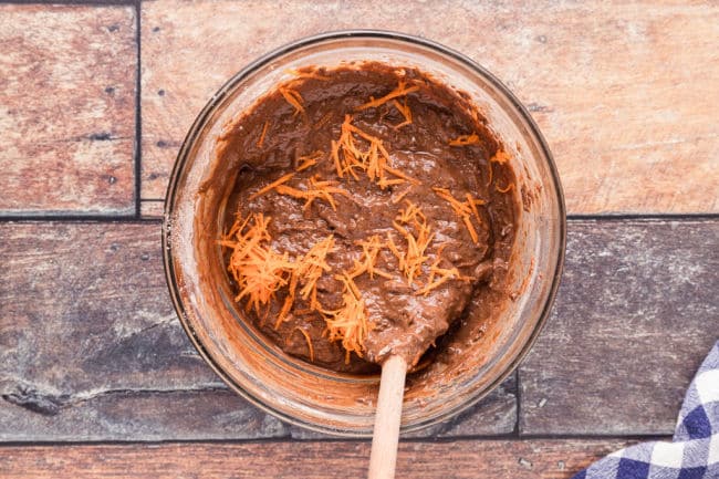 Stirring brownie batter with grated carrot.