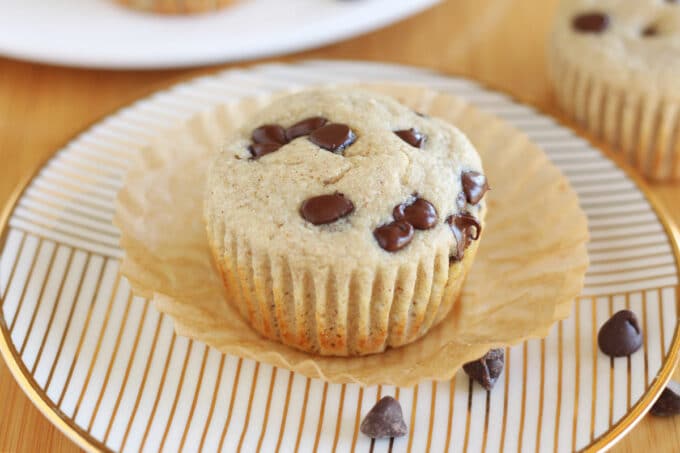 Chocolate chip muffin on a gold striped plate.