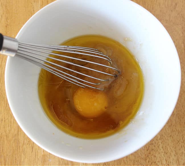 Water, egg, and oil in a small white bowl.