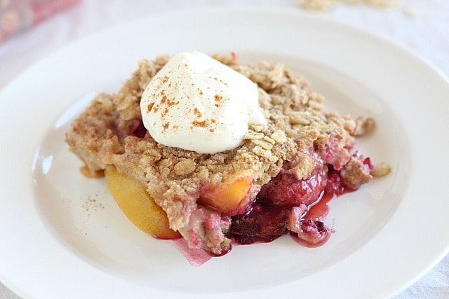 Gluten-free cobbler recipe with peaches and berries on a white plate.