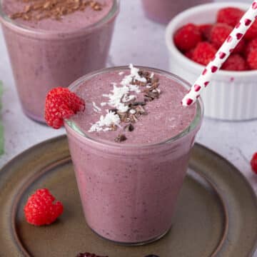 Berry smoothie on a dark plate with a heart straw.