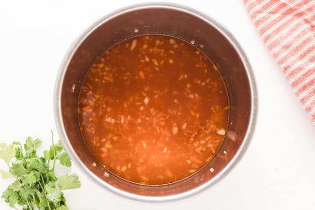 Rice, vegetables, water, and tomato sauce in an Instant Pot.