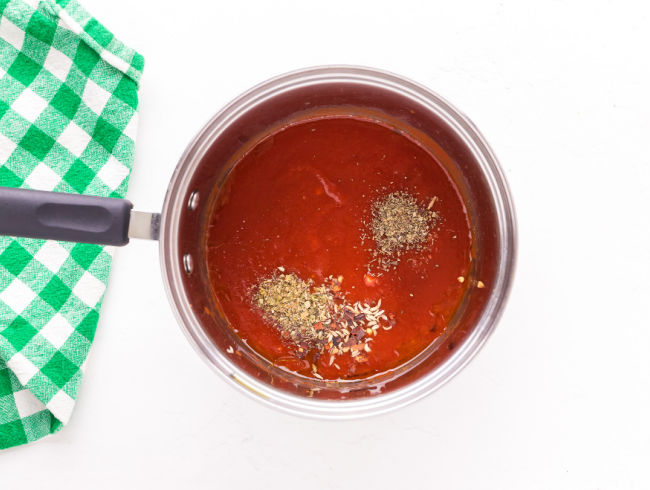 Tomato sauce and spices in a saucepan.
