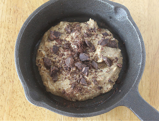 Chocolate chip cookie in a small cast iron skillet.