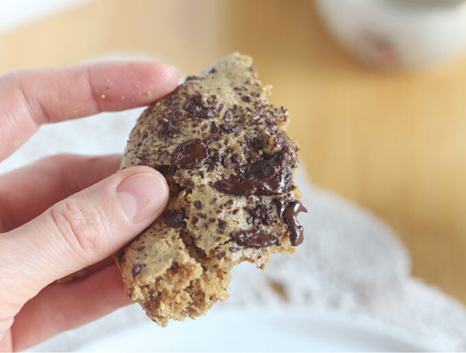 Hand holding a piece of a chocolate chip cookie.
