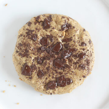 Top down view of chocolate chip cookie on a white plate.