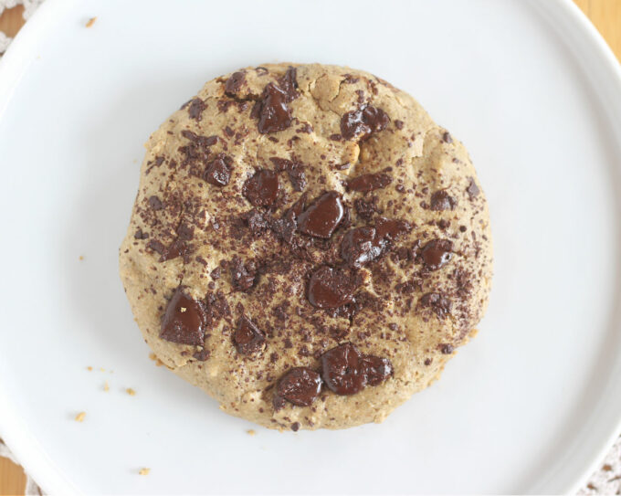 Top down view of chocolate chip cookie on a white plate.