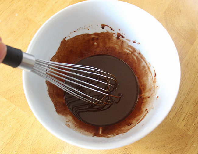 Homemade chocolate being stirred in a white bowl.