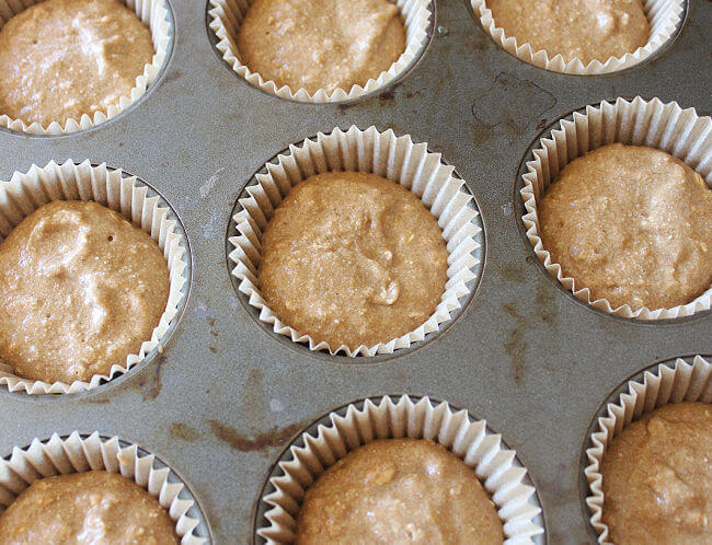 Unbaked muffin batter in paper muffin cups in a tray.