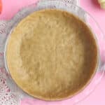 Overhead shot of pie crust with a pink background.